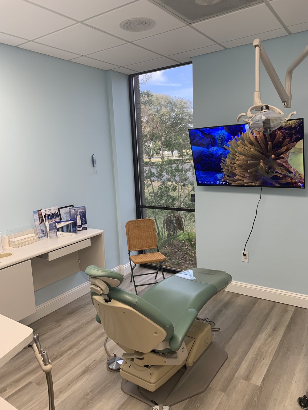Dental treatment room with a green dental chair and windows at Endless Summer Dental Care